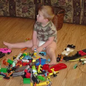 Toddler on the floor with pile of toys.
